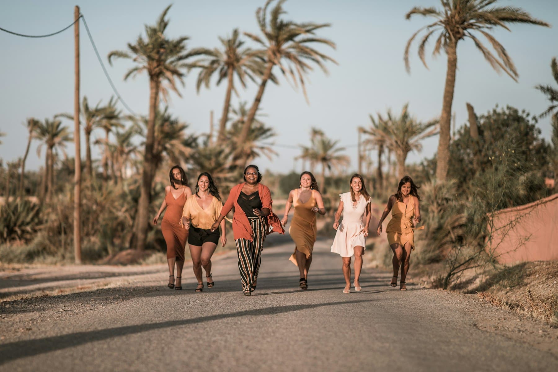A group of women walking together down a palm-lined road